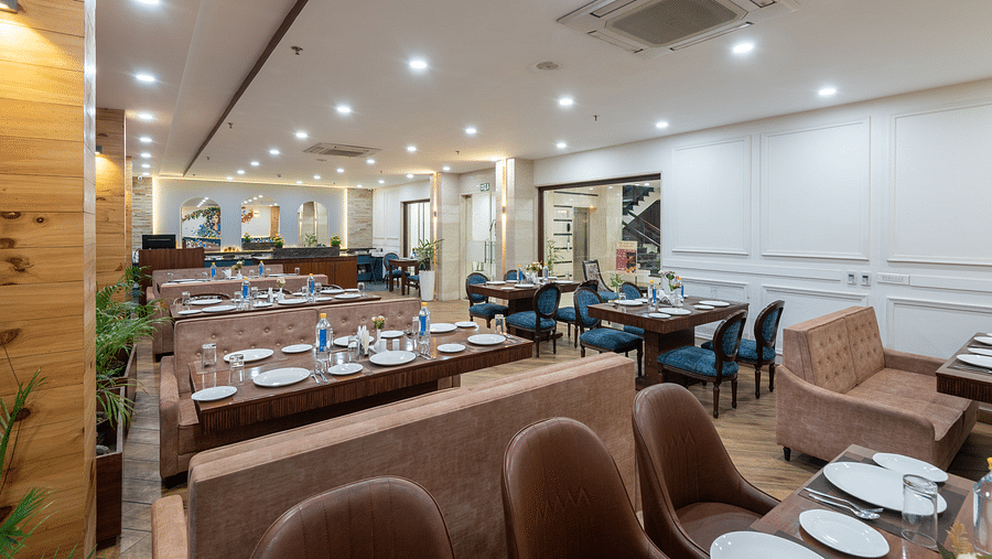 Seating area of a restaurant featuring multiple sofas and chairs with cutlery neatly arranged on the table at DLS The Classio